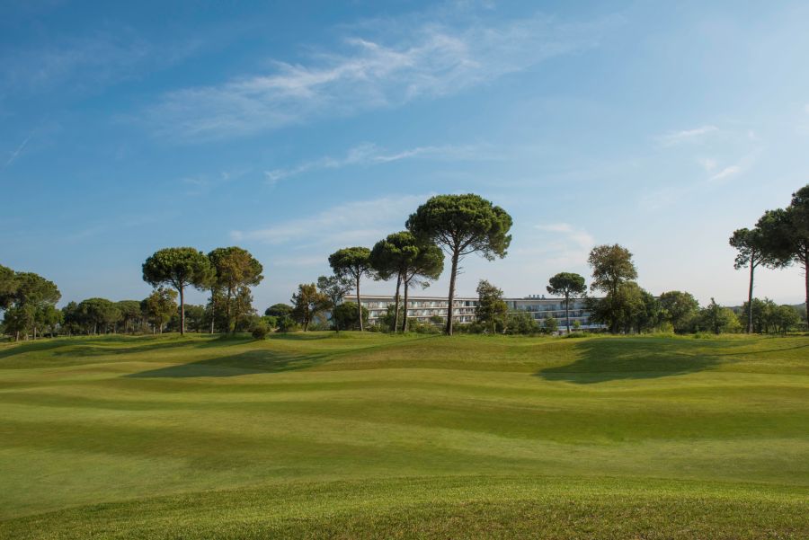 Blue sky and few clouds overlooking the fairway at Camiral Golf with hotel in the distance