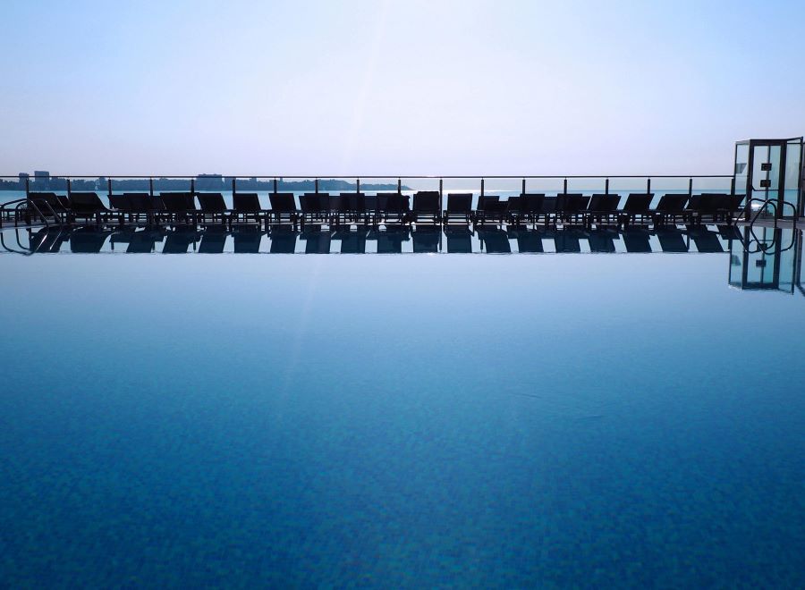 Blue water of outdoor pool with sun loungers in distance at Melia Alicante Hotel
