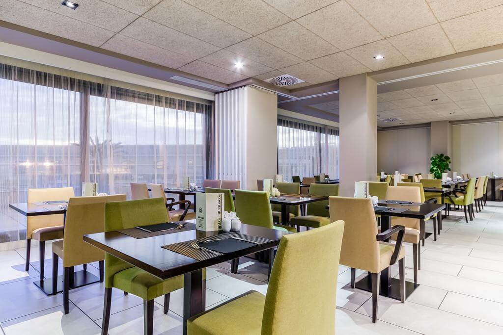Restaurant at 525 Hotel with green chairs and set tables