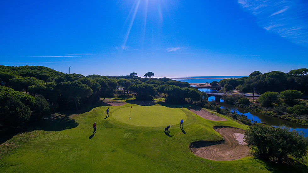 Sea in the distance of the golf course with golfers on the green at Hotel Nuevo Portil Golf