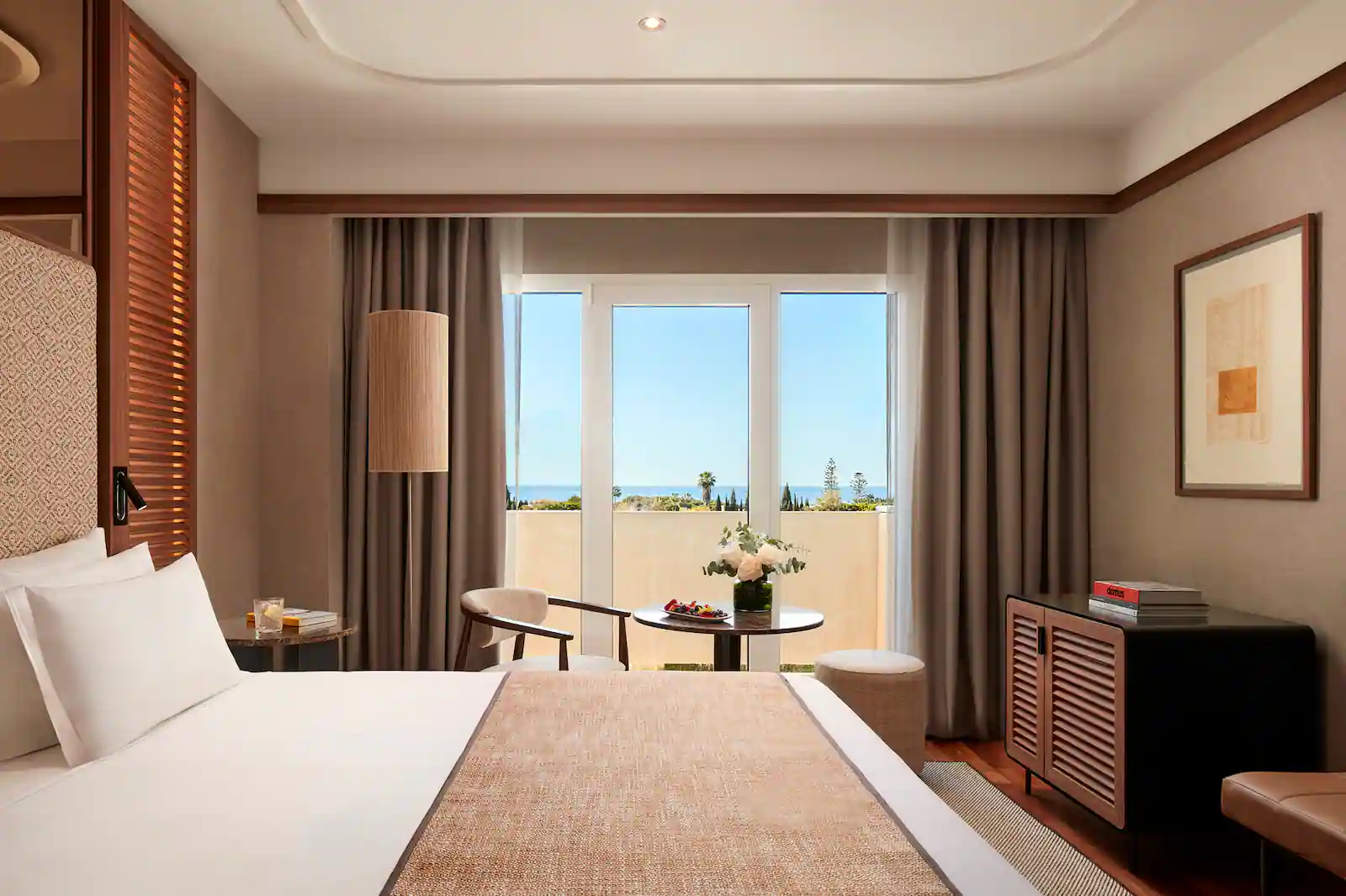 Bedroom with table and chair overlooking view from balcony at NH Collection Marbella