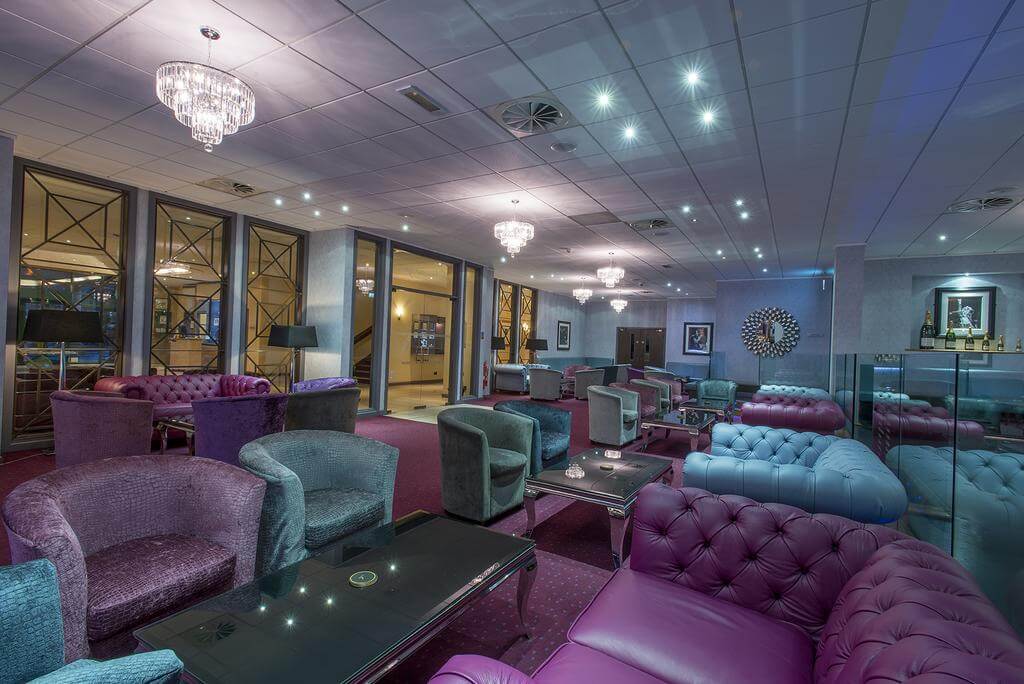 Bar area with purple and blue sofas and chairs at The Vale Resort Wales