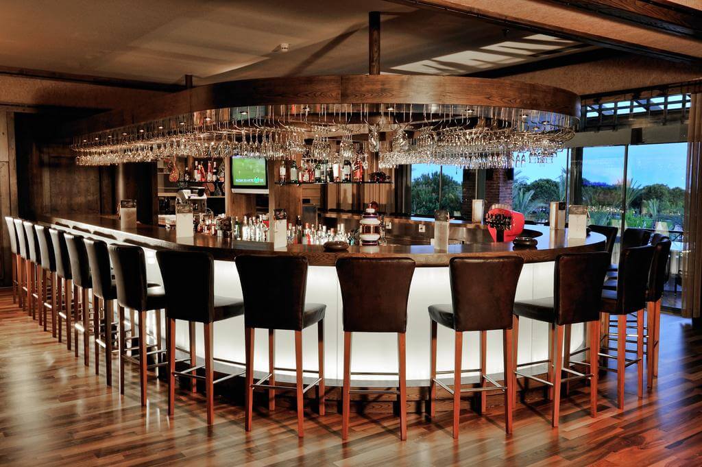 Horse shoe shaped bar with leather stools and television at Gloria Golf Resort