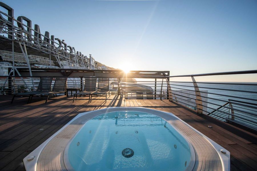 Jacuzzi on rooftop with sun loungers at Sana Sesimbra Hotel