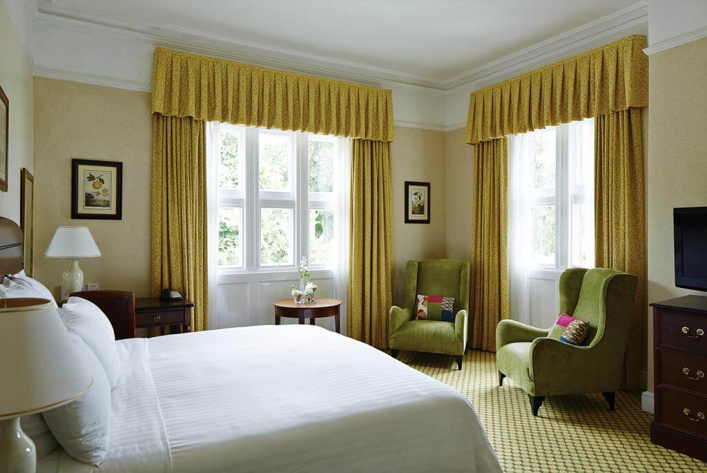 Bedroom with double bed and arm chairs at Breadsall Priory Marriott Hotel And Country Club