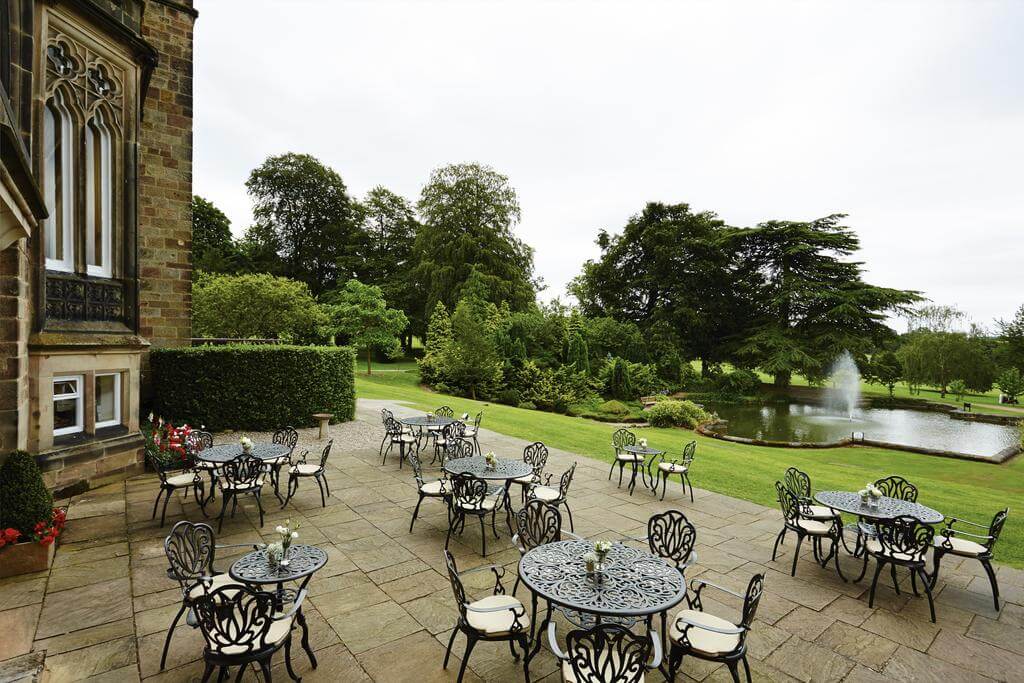 Tables and chairs on the patio overlooking the pond and fountain at Breadsall Priory Marriott Hotel And Country Club