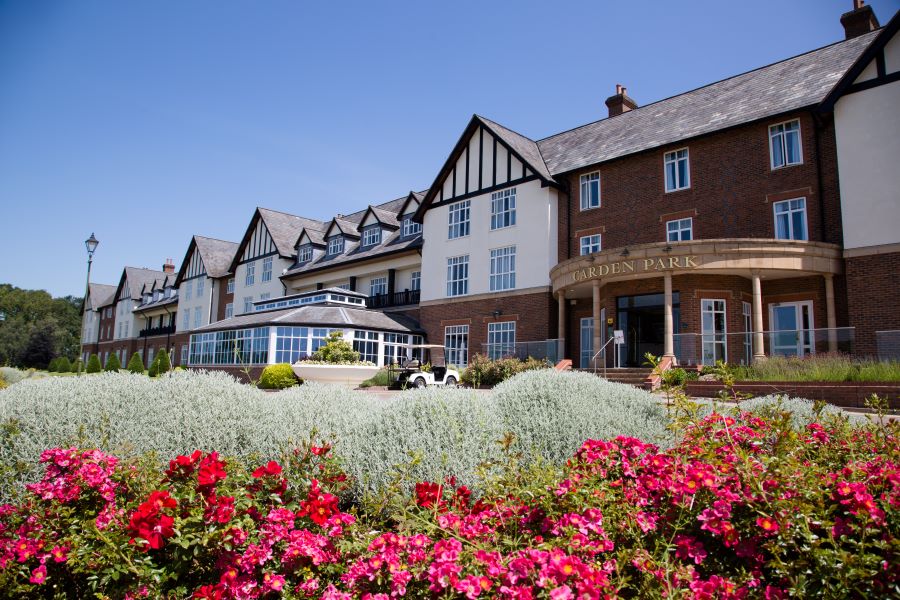 Exterior of Carden Park Hotel in Cheshire with flowers in front of doorway