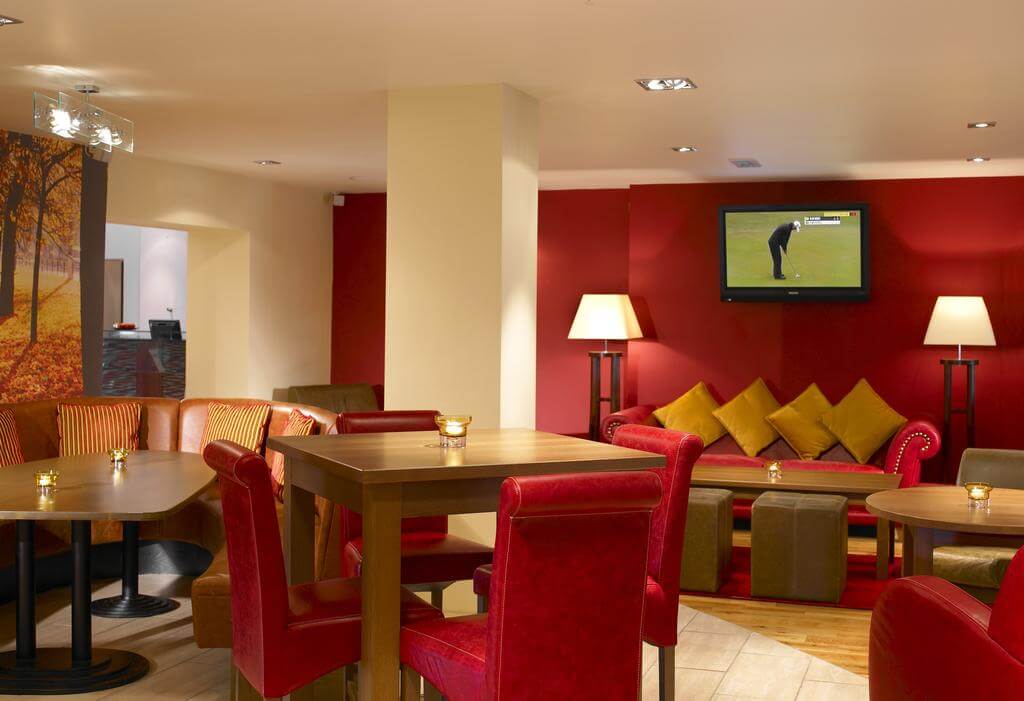 Seating area in the bar with golf on the television at Forest of Arden Marriott Hotel And Country Club