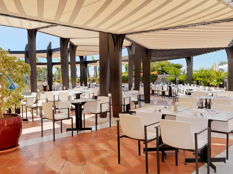 White chairs in restaurant with sun shining outside at H10 Playa Meloneras Horizons Collection