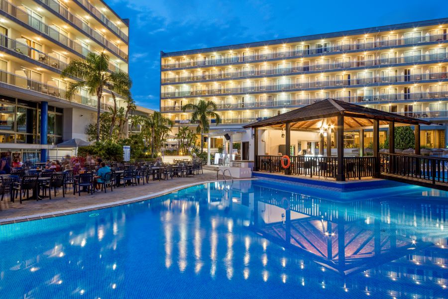 Swimming pool with bar overlooking and rooms lit up by lights at Sol Costa Daurada by Melia