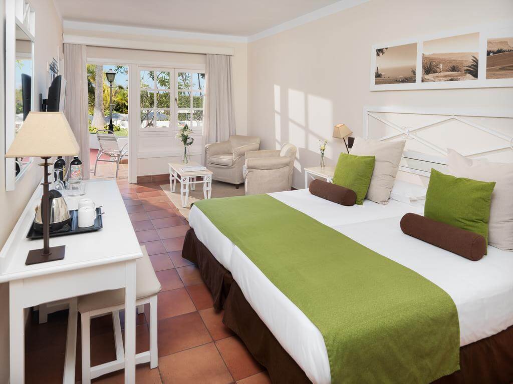 Double bedroom at Hotel Jardin Tecina with tiled floor, white desk, cream chairs and private balcony