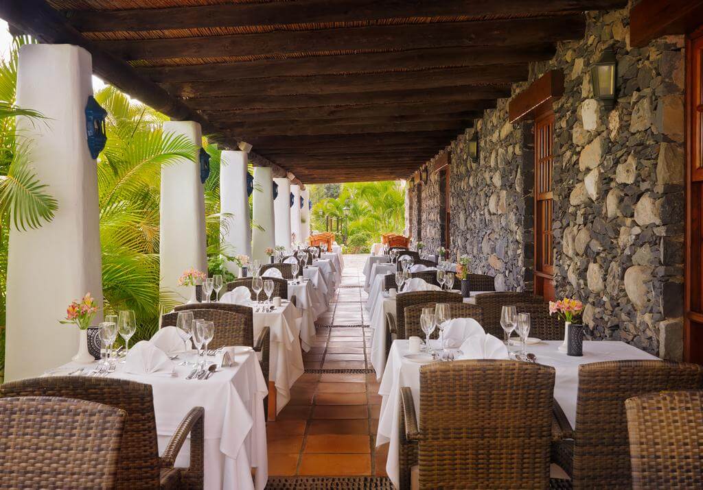 Restaurant at Hotel Jardin Tecina with tables set for guests and brown wicker chairs