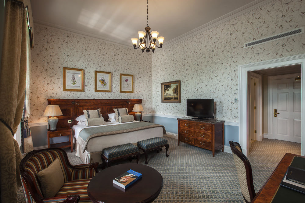 Bedroom with double bed, television, armchair, table, traditional décor and furnishings at The K Club Resort