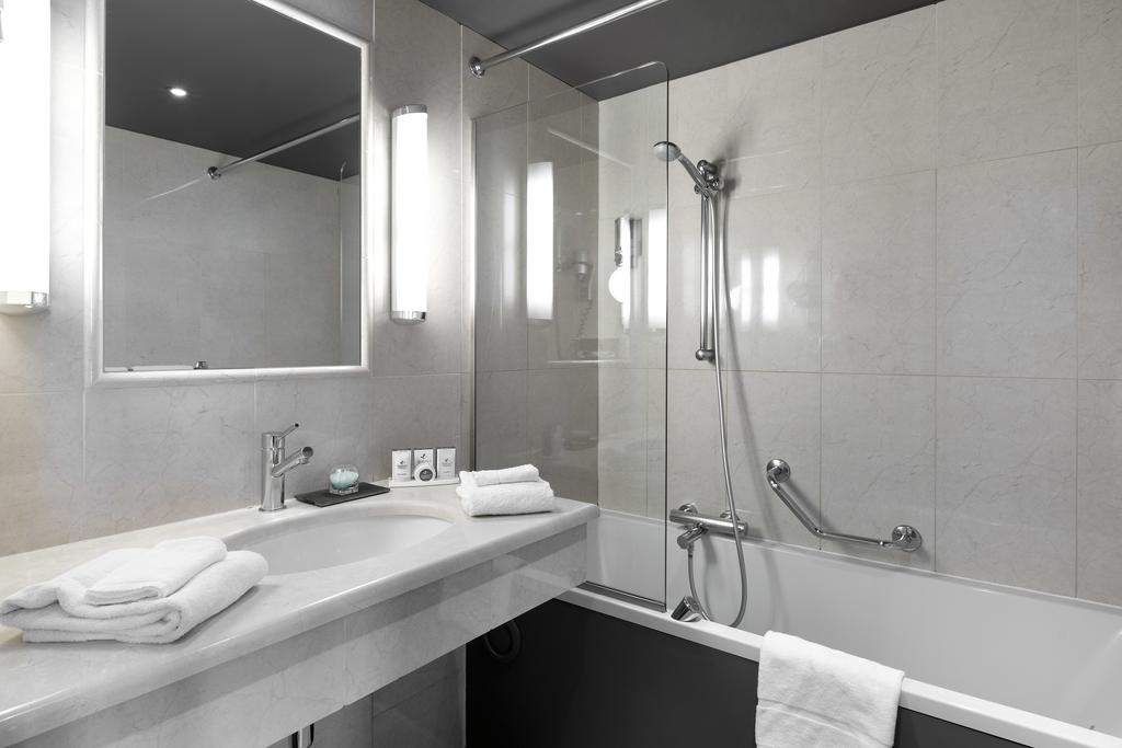 Bathroom at Martin's Brussels EU with shower over bath, sink, mirror on wall and white towels