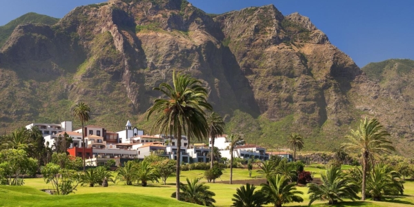 Melia Hacienda Del Conde resort behind the golf course and palm trees with the mountains overlooking