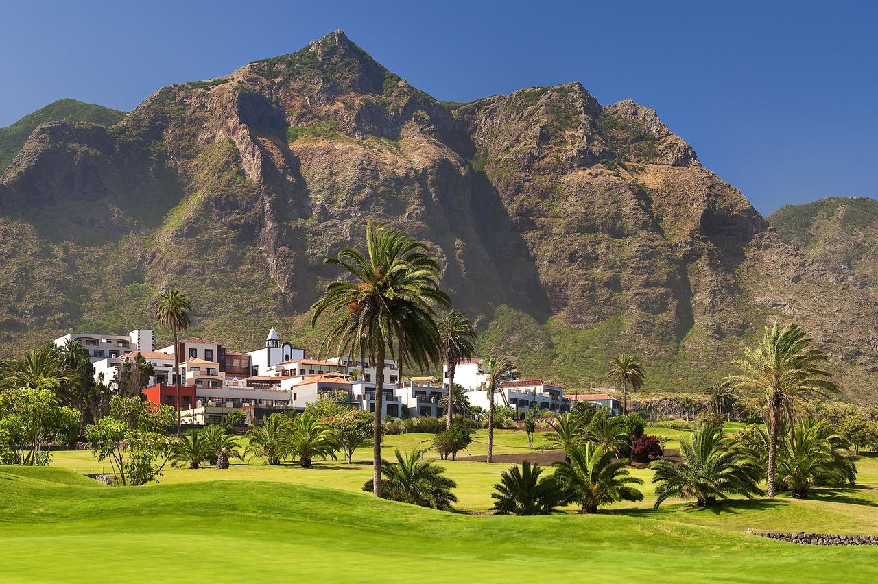 Melia Hacienda Del Conde resort behind the golf course and palm trees with the mountains overlooking