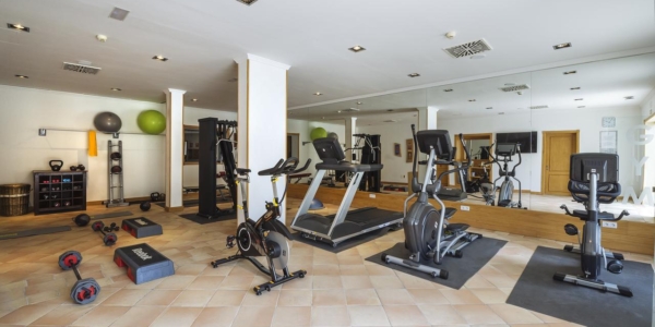 Melia Hacienda Del Conde's gym with cardio machines, free weights and mirrored wall