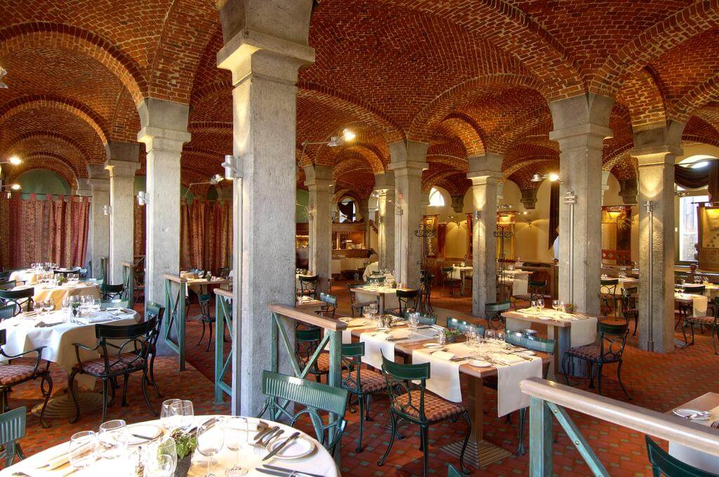 Martin's Grand Hotel restaurant with concrete pillars, exposed brick arched ceiling, green chairs and tables set