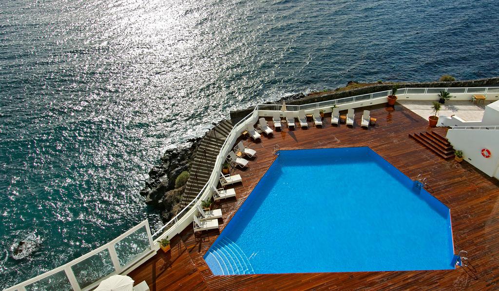 Vincci Tenerife Golf's wooden pool area with sun loungers and sea