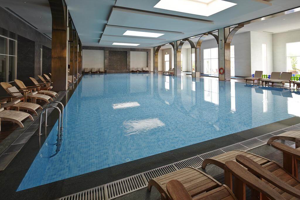 Indoor swimming pool with loungers at Titanic Deluxe Golf Belek