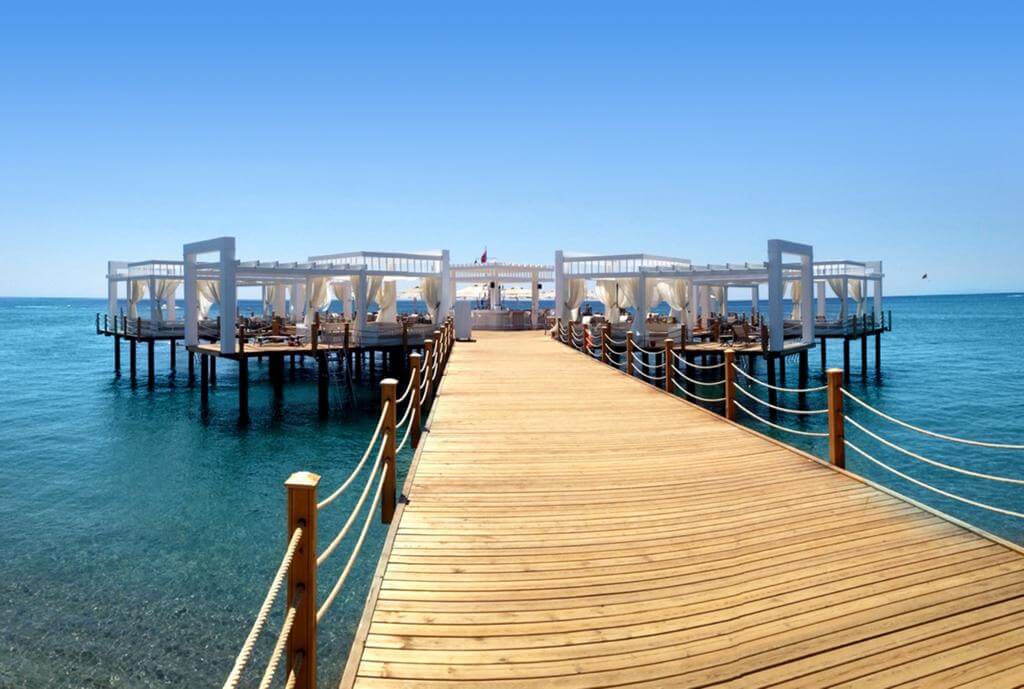 Walkway on the wooden pier leading to sun loungers overlooking the sea Kempinski Hotel The Dome in Belek