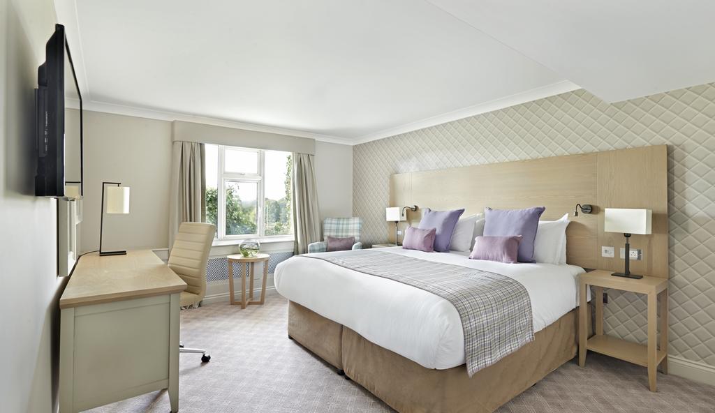 Bedroom with double bed decorated with cushions, flat screen television and desk with chair at The Belfry