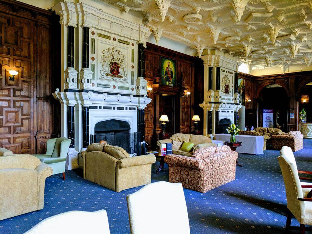 Wood panelled seating area with sofas and open fire at Broome Park Hotel