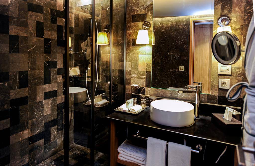 Tiled bathroom at Hotel Sofitel Marrakech Lounge And Spa separate shower cubicle, sink, towels and toiletries