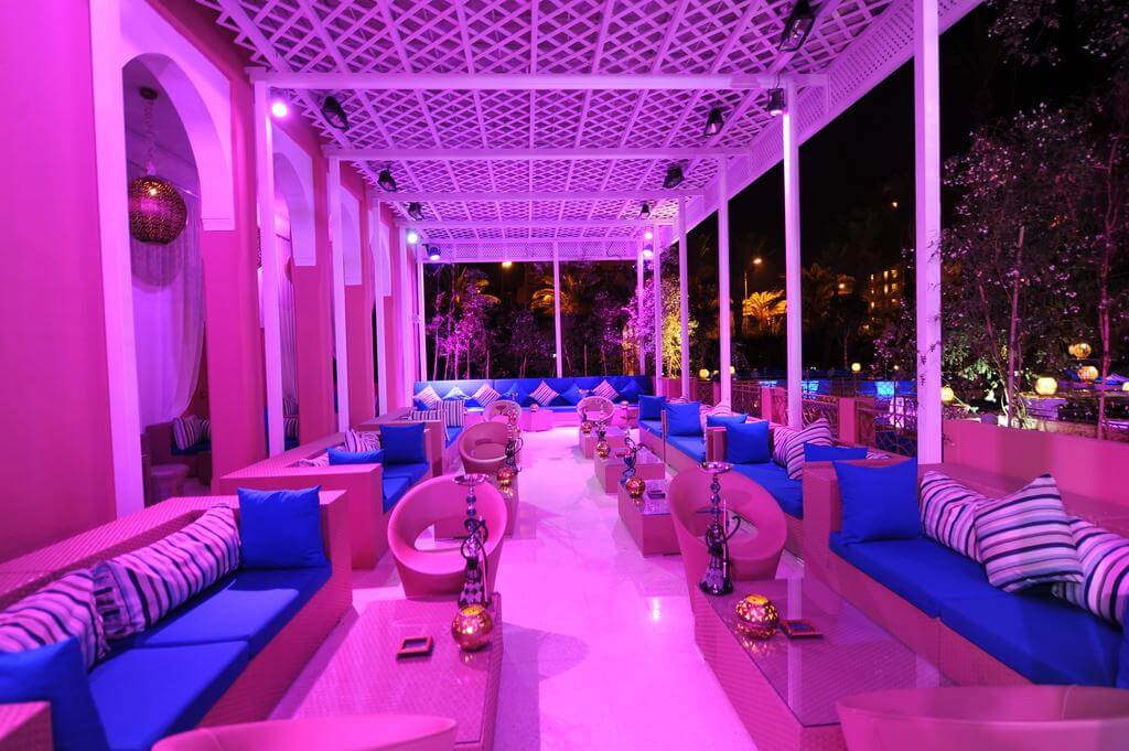 Hotel Sofitel Marrakech Lounge And Spa outdoor seating area at night with blue cushions, shisha pipes, and candles