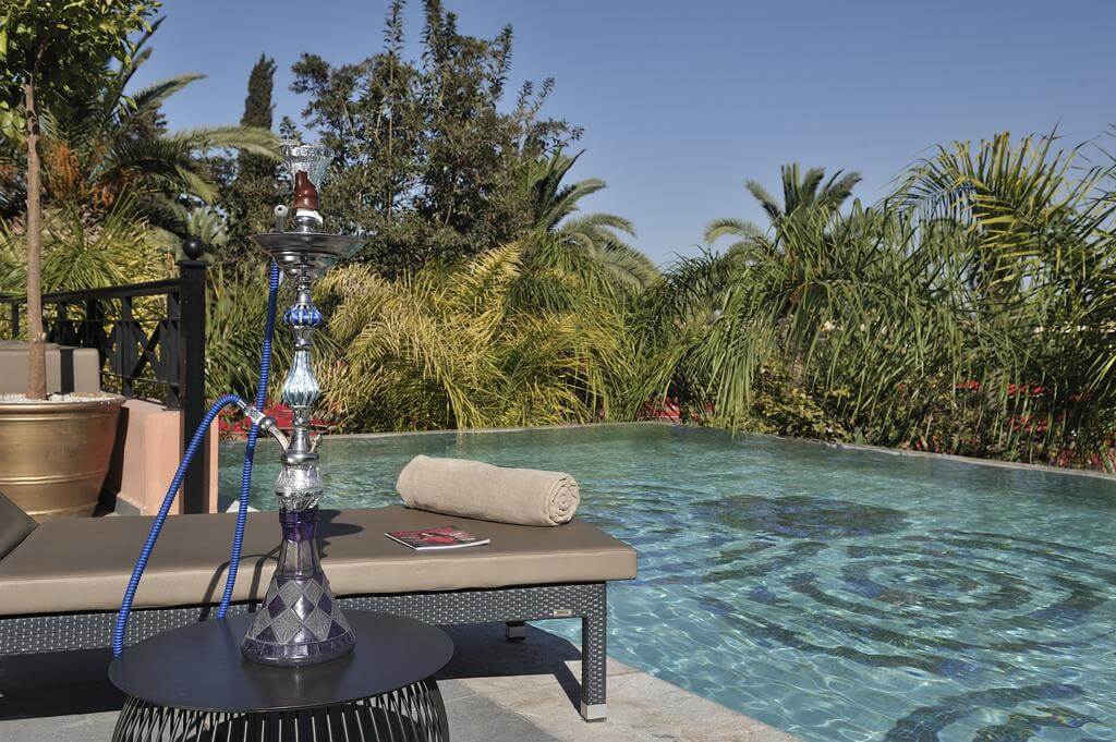 Hotel Sofitel Marrakech Lounge And Spa swimming pool with rolled up towel on sun lounger and shisha pipe