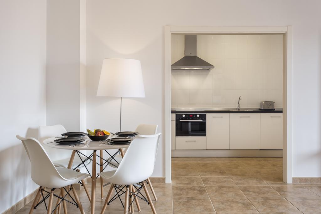 Kitchen in the background with dining table and cutlery laid out in the foreground at The Residences Islantilla Apartments