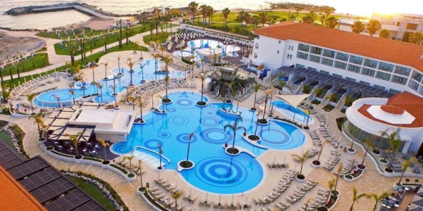 Olympic Lagoon Resort Paphos overlooking pool area, sun loungers, palm trees, beach and sea