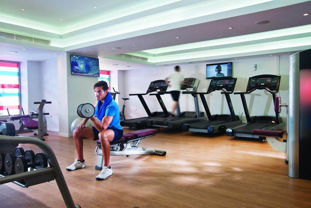 Two guests working out in gym at Olympic Lagoon Resort Paphos with free weights and cardio machines