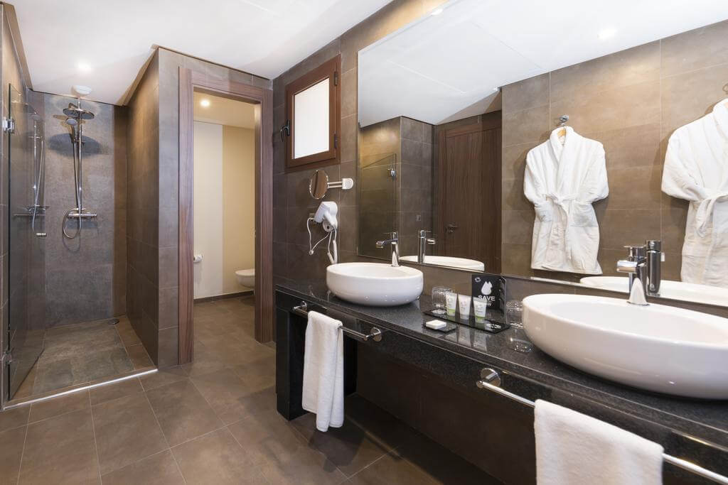 Bathroom at Be Live Experience Marrakech Palmeraie with seperate shower cubicle, twin sinks, two bathrobes, toilet cubicle, and hair dryer