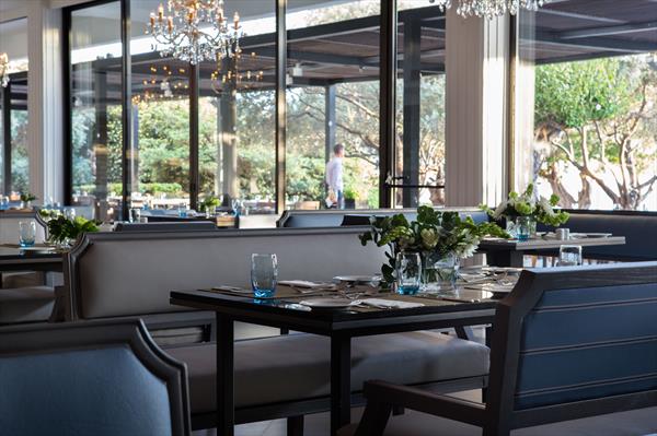 Dining table in restaurant at Almyra Hotel with table set, blue chairs, and flowers on the table