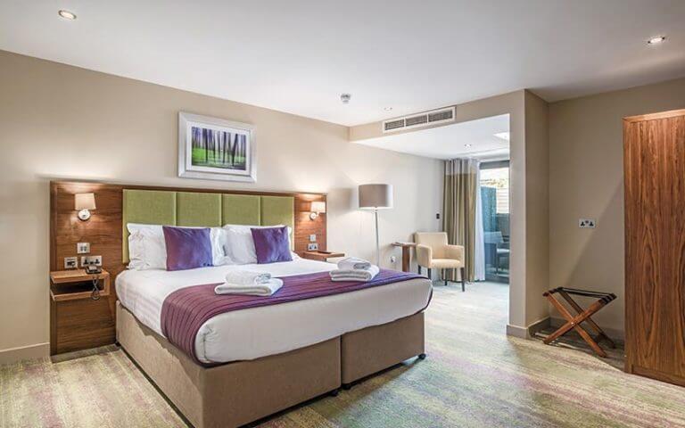 Double bedroom with fresh towels on the bed at Cotswolds Hotel Spa And Golf