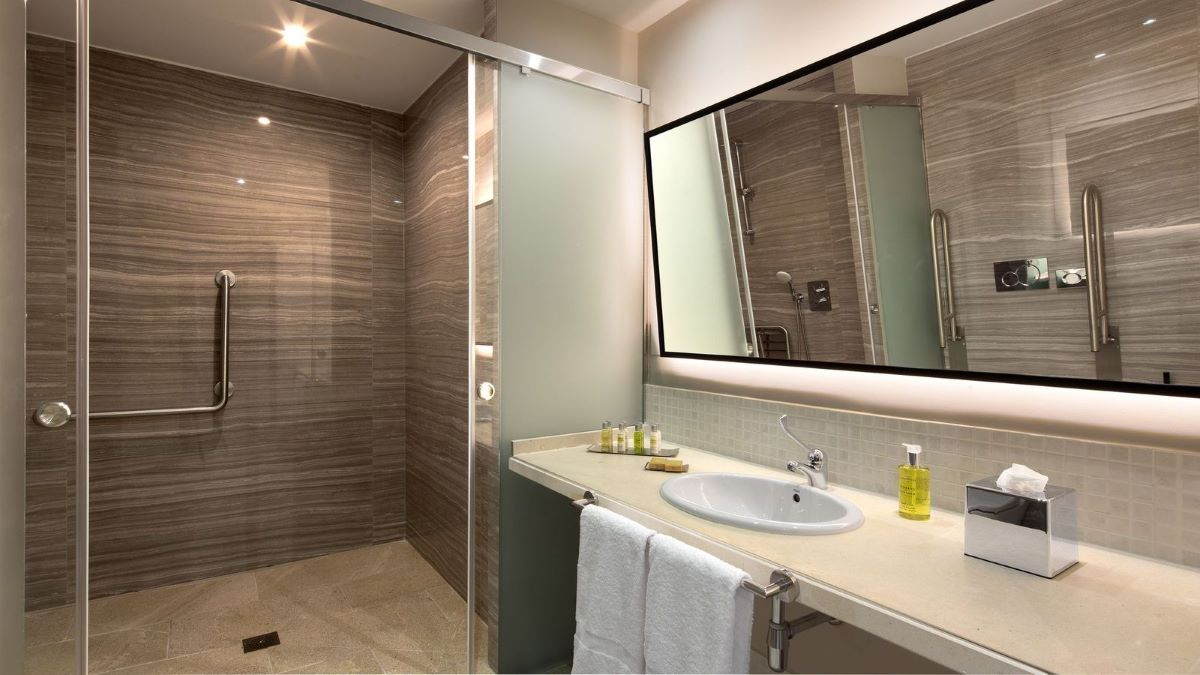 Tiled bathroom at DoubleTree by Hilton Islantilla Beach Golf Resort with sink, mirror, and shower cubicle