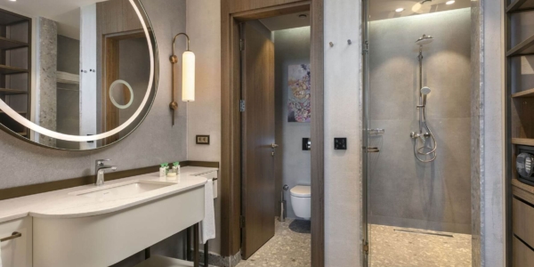 Bathroom at Cullinan Belek with separate toilet and shower cubicles, round mirror and sink