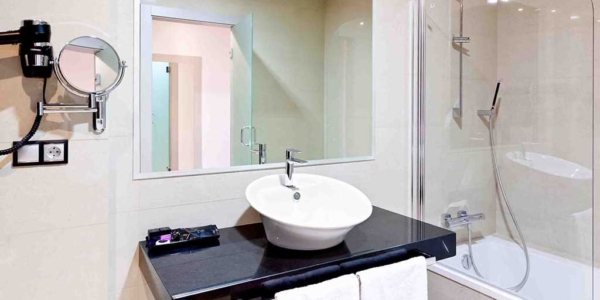 Bathroom at DNA Monse Hotel Spa And Golf with mirror on wall, sink, shower over bathtub and clean towels