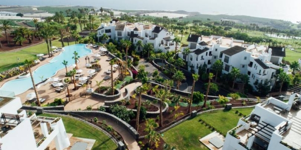 Ariel shot of Las Terrazas de Abama Suites showing the pools, palm trees, white wash buildings and golf course