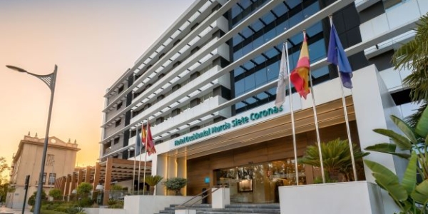 Exterior of Hotel Occidental Murcia Siete Coronas at sunset with flags outside the reception