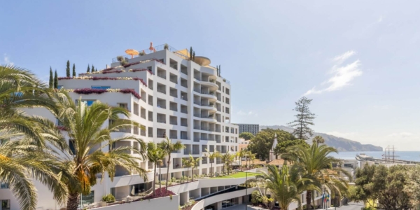 Exterior of NEXT By Savoy Signature with blue sky and palm trees