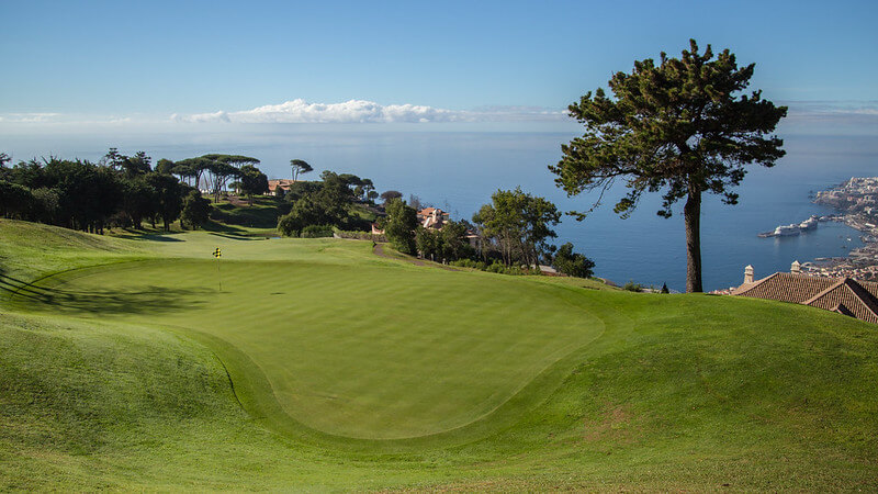 Golf green with sea in the background and trees surrounding
