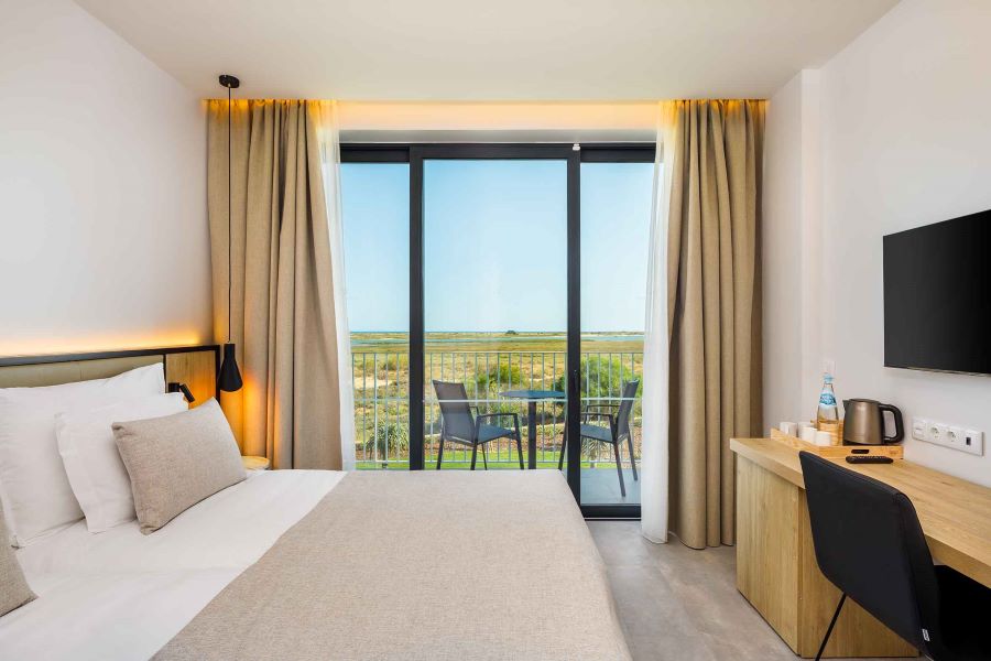 Bedroom with television on the wall and views out onto the terrace at AP Cabanas Beach & Nature in Tavira