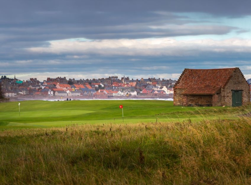 Dunbar Golf Club with the town in the distance, and the flag on the green in the foreground