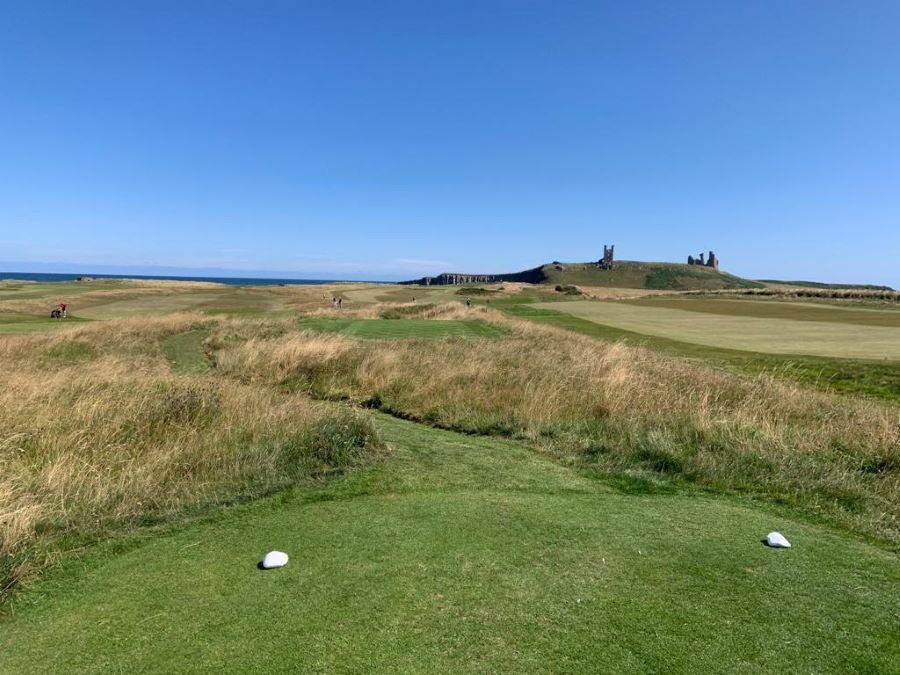 Ruined Dunstanburgh Castle in the background of the tee at the golf club