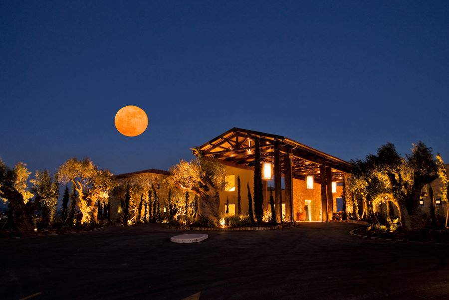 Clubhouse lit up at night with moon at Costa Navarino The Dunes course