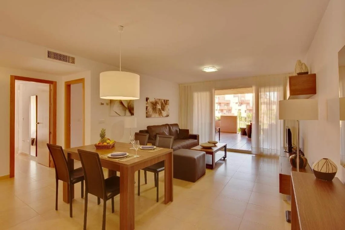 Dining table, sofas and television in apartment at Ona The Residences at Mar Menor Golf Resort in Murcia