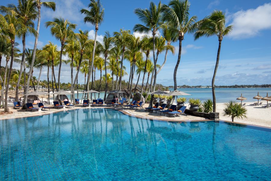 Swimming pool with palm trees overhanging the sun loungers at Shangri-La Le Touessrok