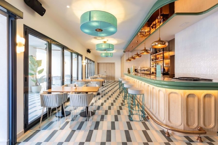 Bar with tables and green stools at Hotel Angela